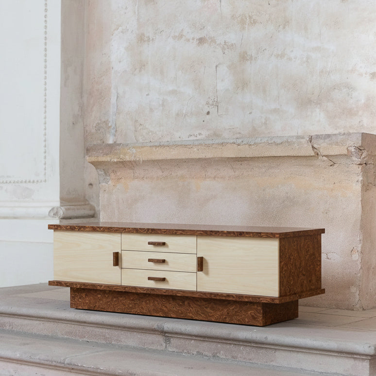 Wooden sideboard with cream-colored doors against a stone wall background